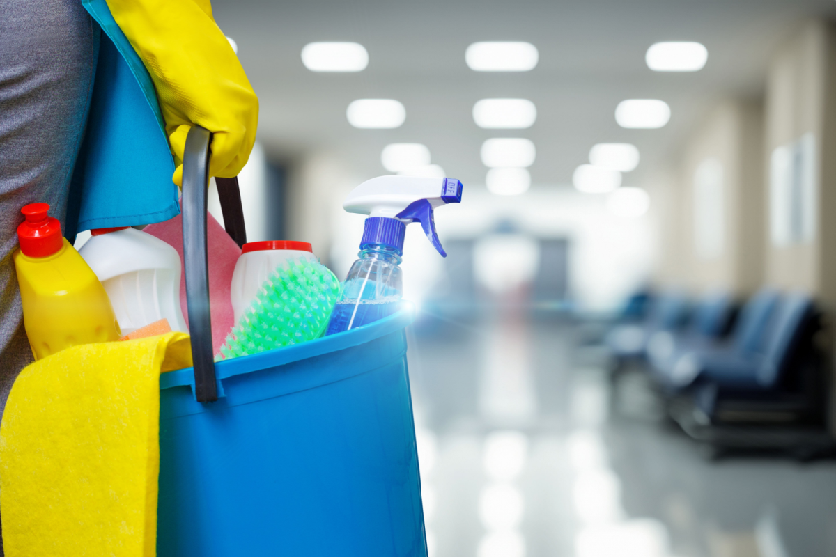 Cleaning person coming into an office armed with cleaning supplies